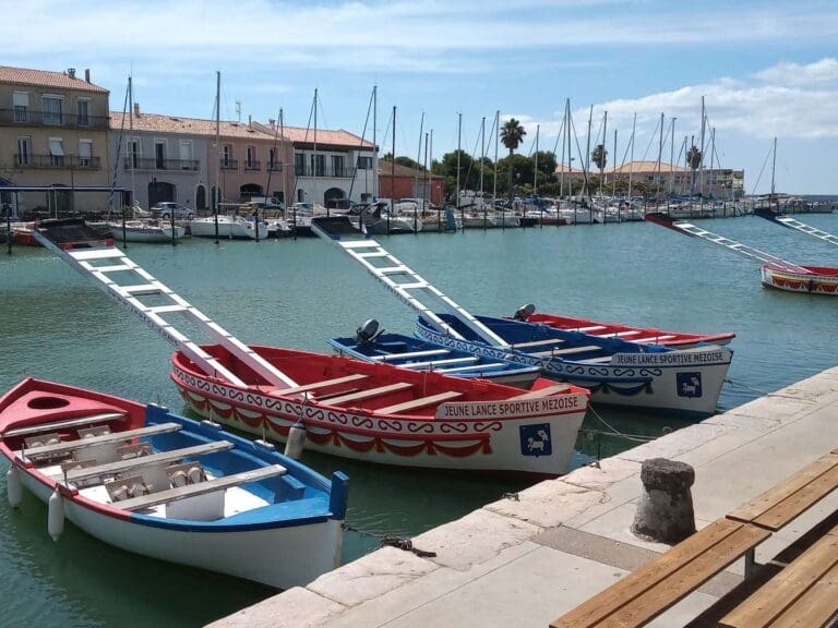 Barques de joute rouges, blanches et bleues amarrées au quai du port de Mèze
