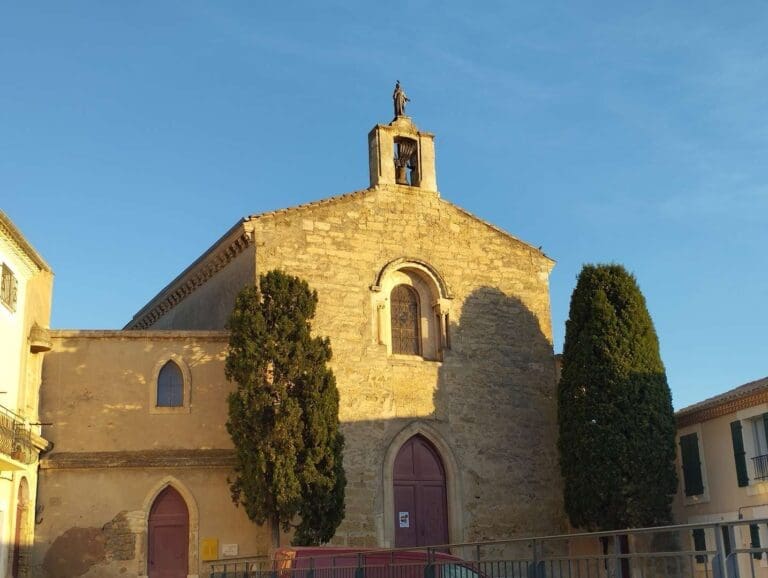 Chapelle en pierre dorée entourée de cyprès dans le centre de Mèze