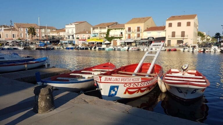 Barques rouges et blanches amarrées devant les façades du port de Mèze