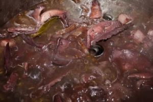 Seiche mijotant dans le vin rouge avec lardons, laurier et olives noires