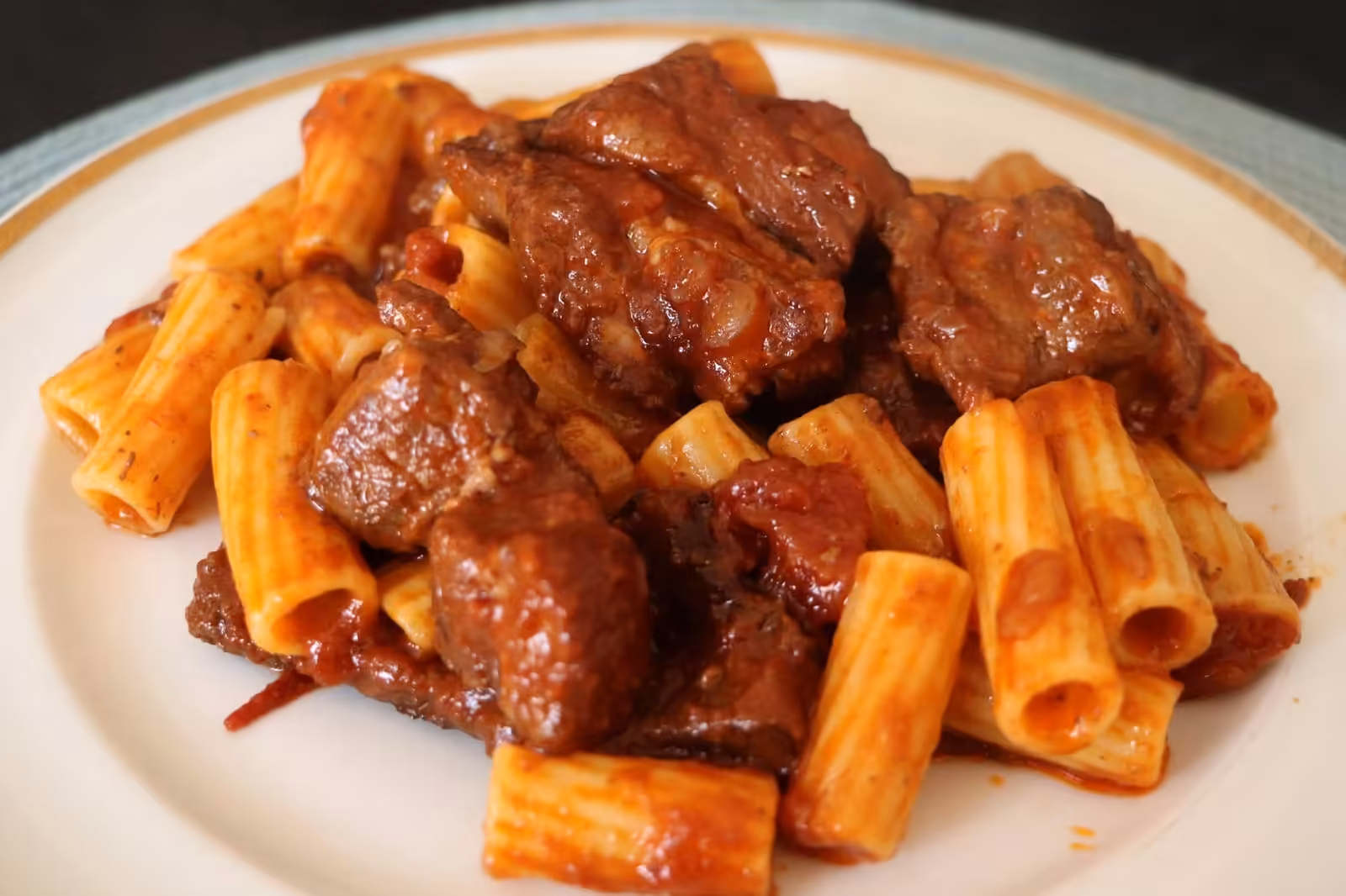 Assiette de macaronade rapide, rigatoni et morceaux de viande en sauce tomate