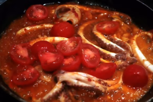 Tomates cerises ajoutées sur les poulpes de roche qui mijotent dans leur jus