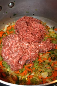 Bœuf haché et chair à saucisse ajoutés sur le hachis de légumes