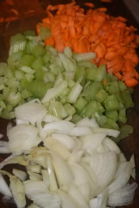 Carottes, céleri et oignon hachés sur une planche pour le ragù bolognaise