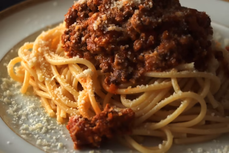 Gros plan de spaghettis nappés de ragù bolognaise et de parmesan râpé