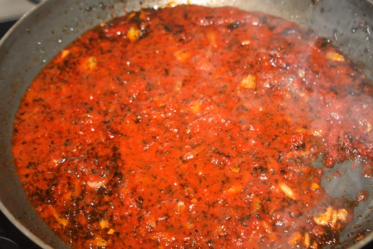 Sauce tomate et persil en réduction dans la poêle pour la farce de la tielle