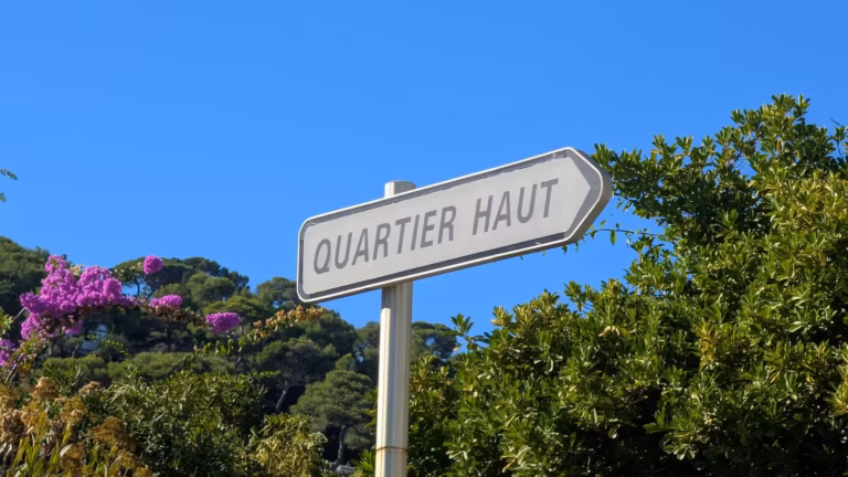 Panneau indicateur Quartier Haut parmi des buissons en fleurs